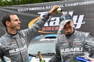 Codriver Craig Drew showers driver David Higgins with Champagne at Olympus podium Codriver Craig Drew showers driver David Higgins with Champagne at Olympus podium
